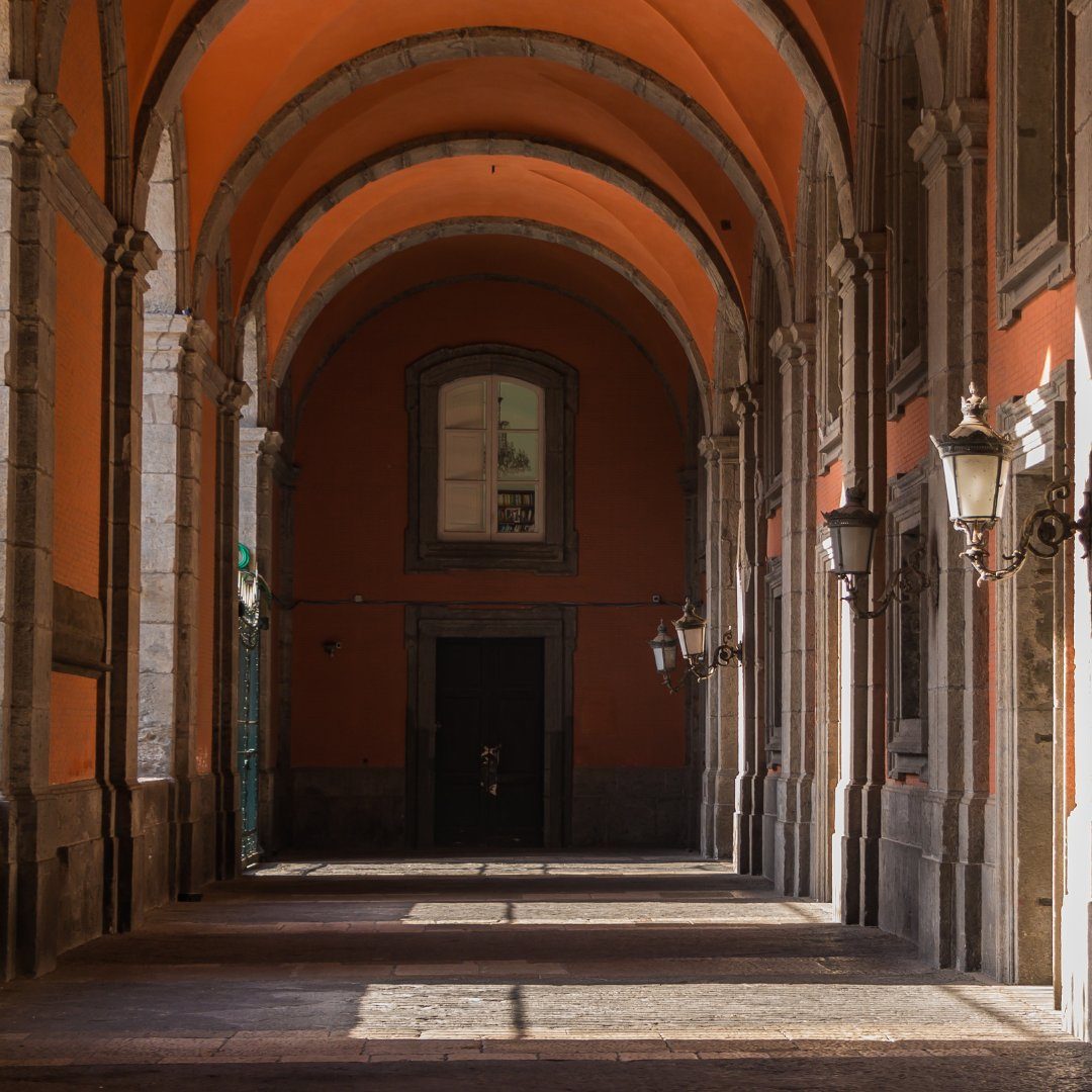 Vaulted terracotta portico of the Royal Palace of Naples with iron lanterns