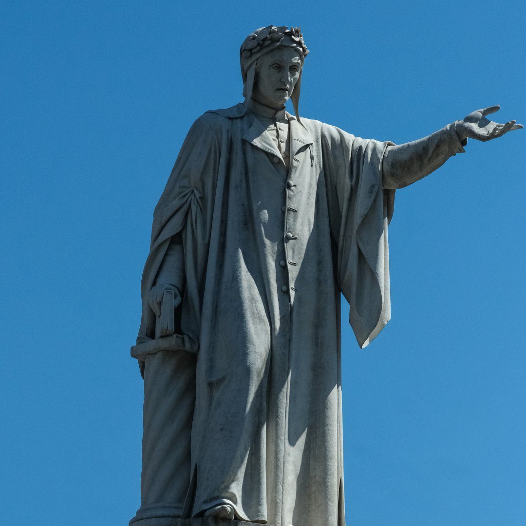 Marble statue of Dante Alighieri against a clear blue sky in Piazza Dante, Naples